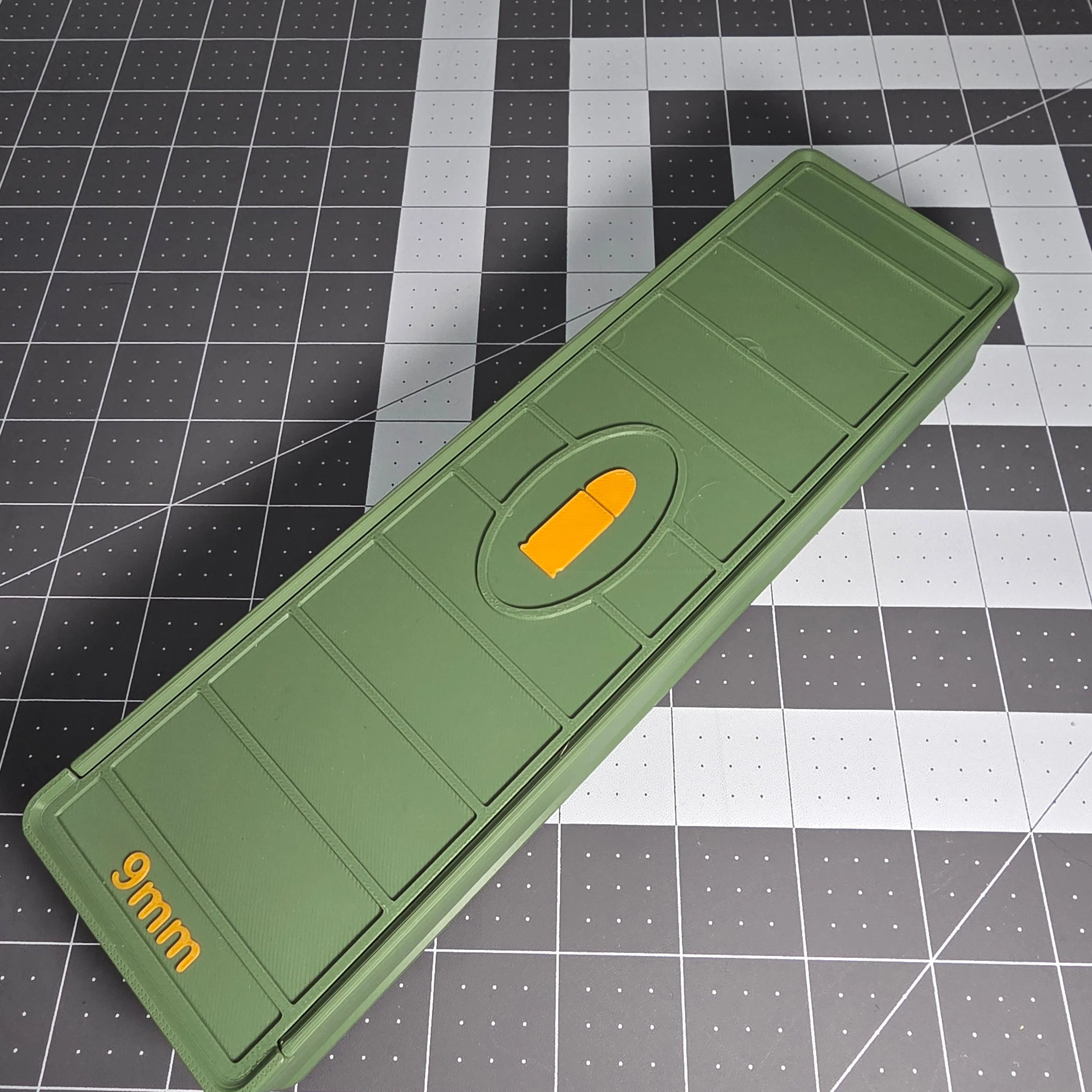 Green 3D-printed 9mm ammo storage box with yellow bullet symbol on a grid background.