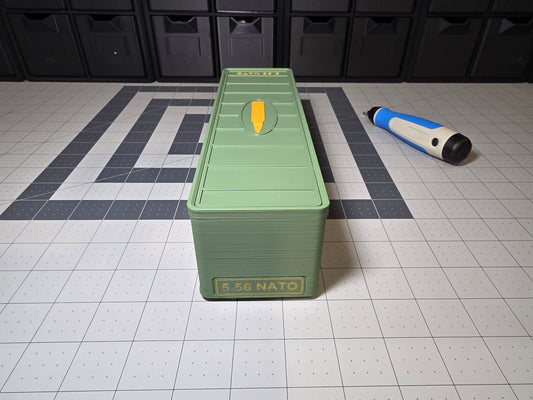 Closed long olive green 5.56 NATO 100-round ammo storage case, front view with 5.56 NATO label and cartridge icon on the lid, 3D printed by SquigglePrintz