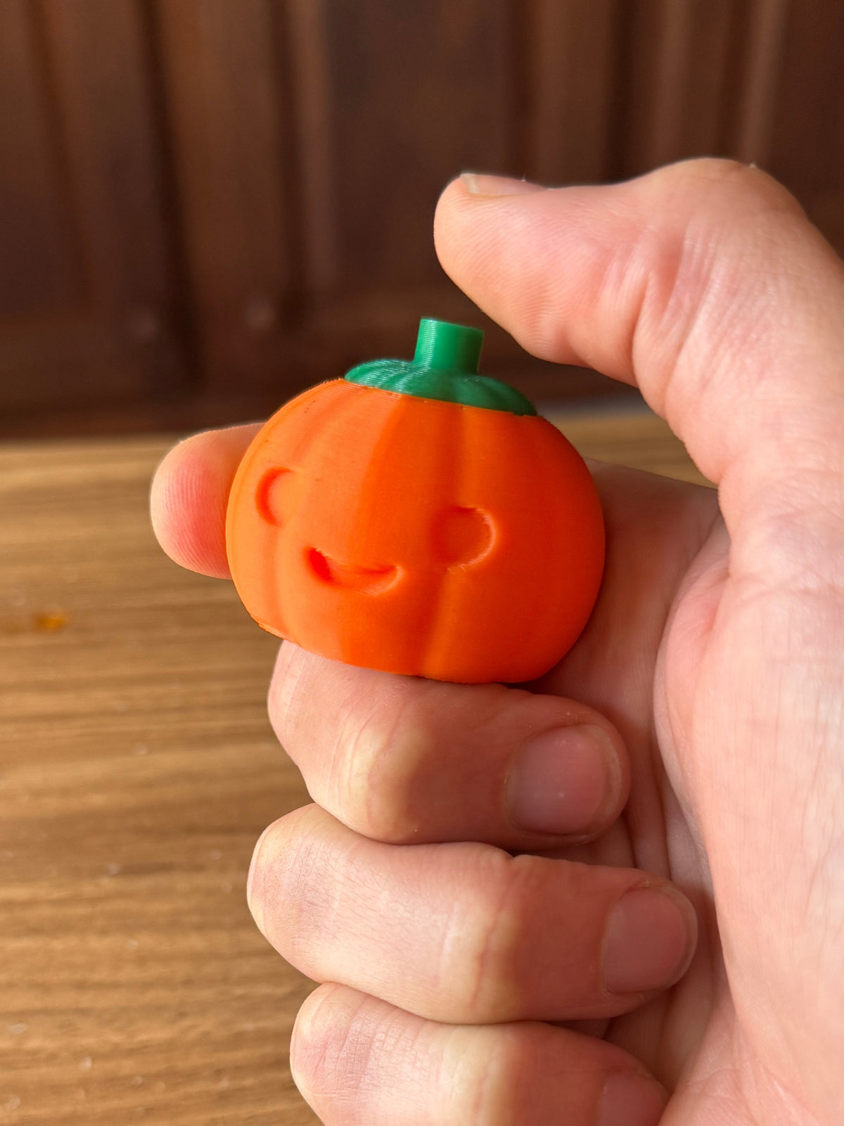 Pumpkin fidget clicker shown in hand, full resolution product photo.