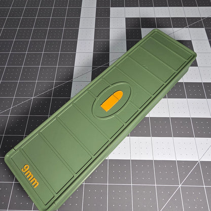 Green 3D-printed 9mm ammo storage box with yellow bullet symbol on a grid background.
