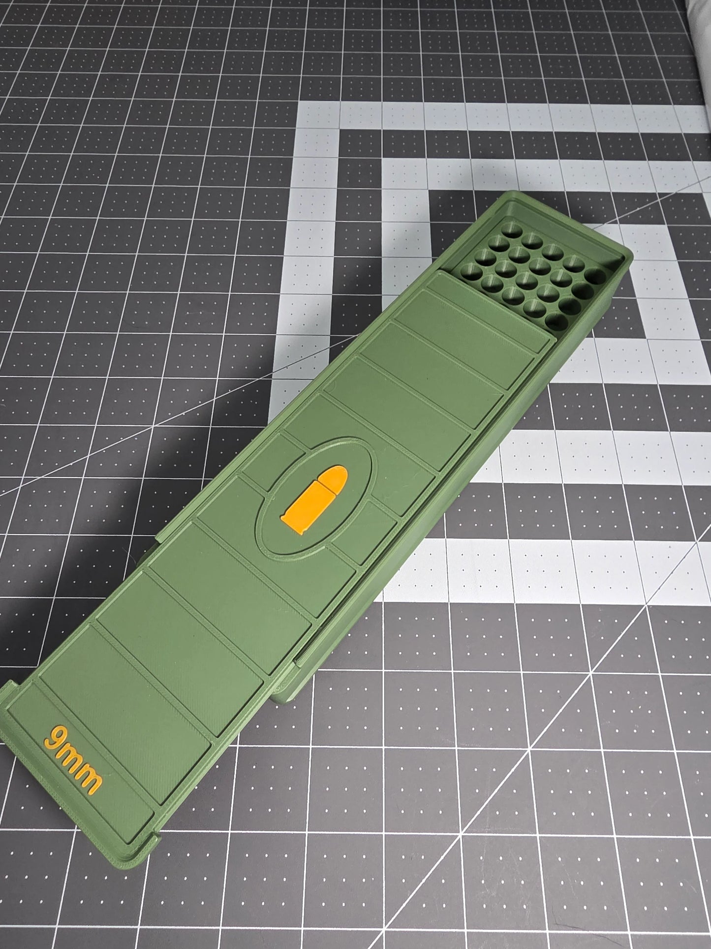 Green 3D-printed 9mm 100-round ammo storage box with orange accents on a grid mat.