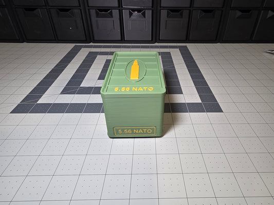 Closed olive green 3D printed 5.56 NATO ammo storage case with 5.56 NATO text on the lid and front, yellow cartridge icon, by SquigglePrintz