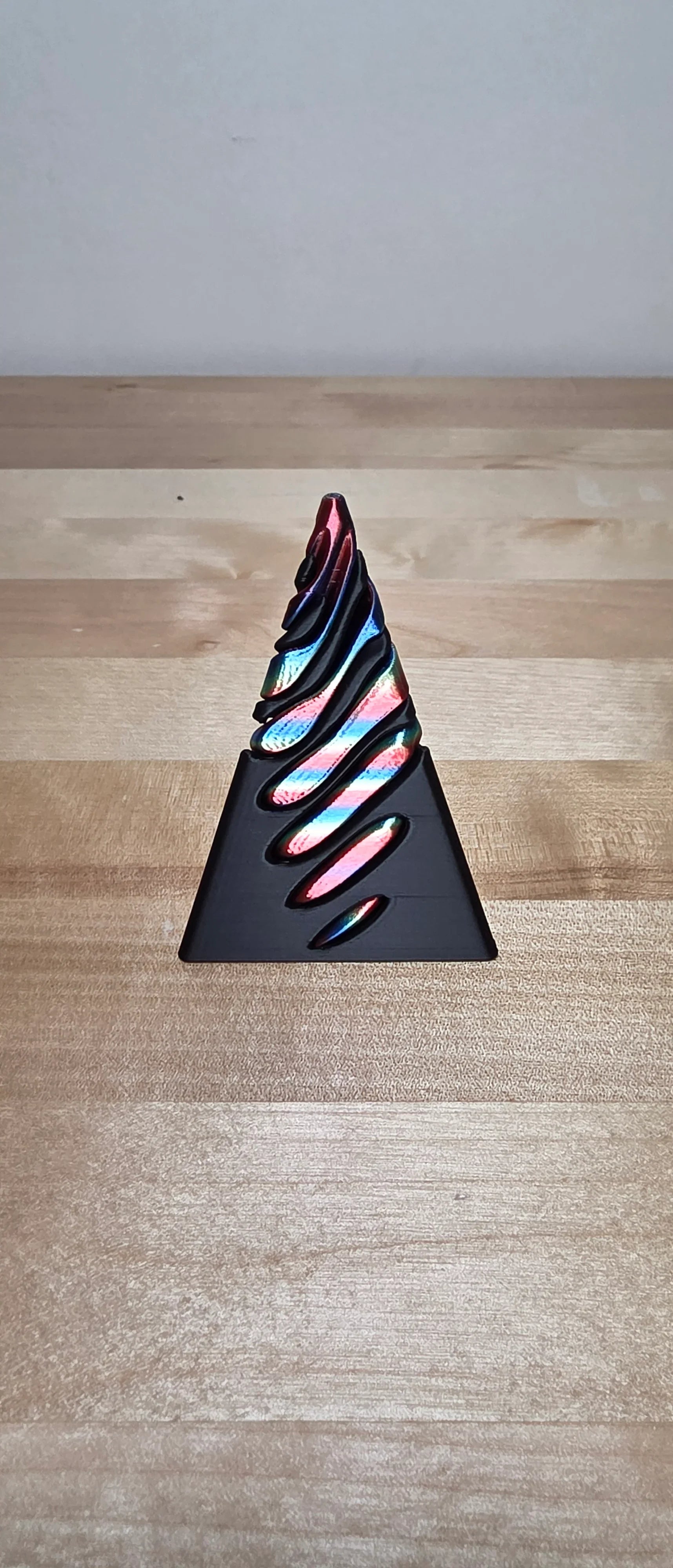 3D-printed spiral rainbow sculpture on wood surface, modern geometric decor